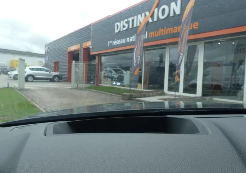 Vue depuis l'intérieur du DS4 2024 gris métallisé, montrant le tableau de bord et la vitrine du concessionnaire Distinxion.
