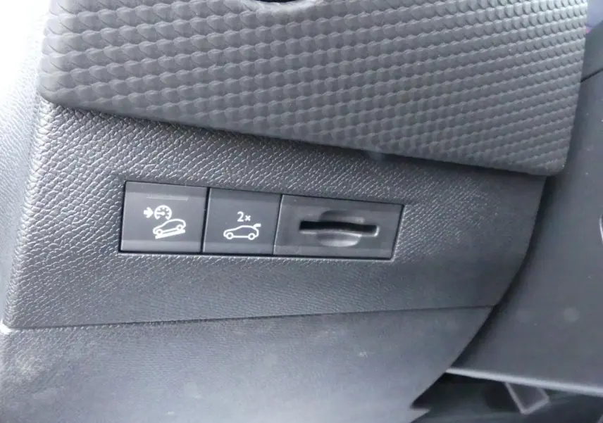 Gros plan sur les commandes de régulateur de vitesse et ouverture du coffre dans l'habitacle du DS4 gris métallisé 2024.