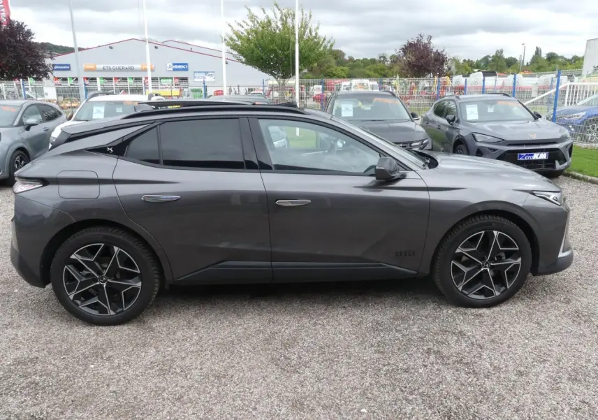 Profil côté gauche d'une DS4 Cross Rivoli gris métallisé avec jantes alliage 19 pouces sur parking extérieur.