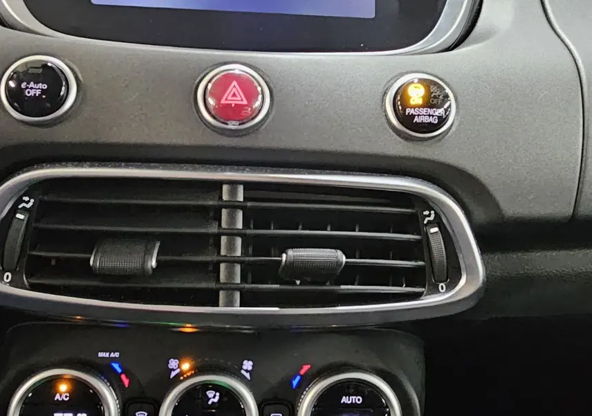 Détail du tableau de bord de la FIAT 500X 2024 montrant les commandes de climatisation et les aérateurs centraux noirs.