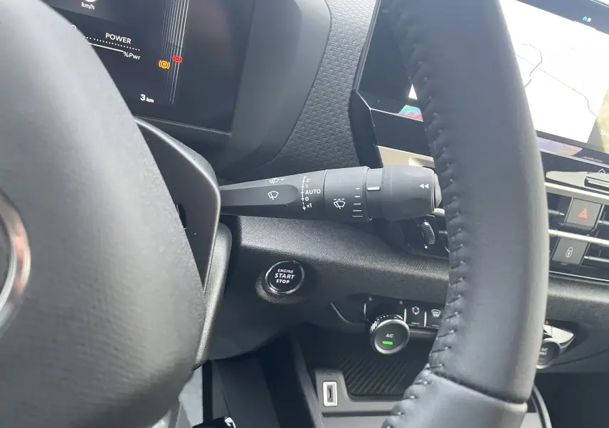 Vue rapprochée de l’intérieur du Citroën C4 hybride 2025, montrant le volant, le bouton start/stop et les commandes du tableau de bord.