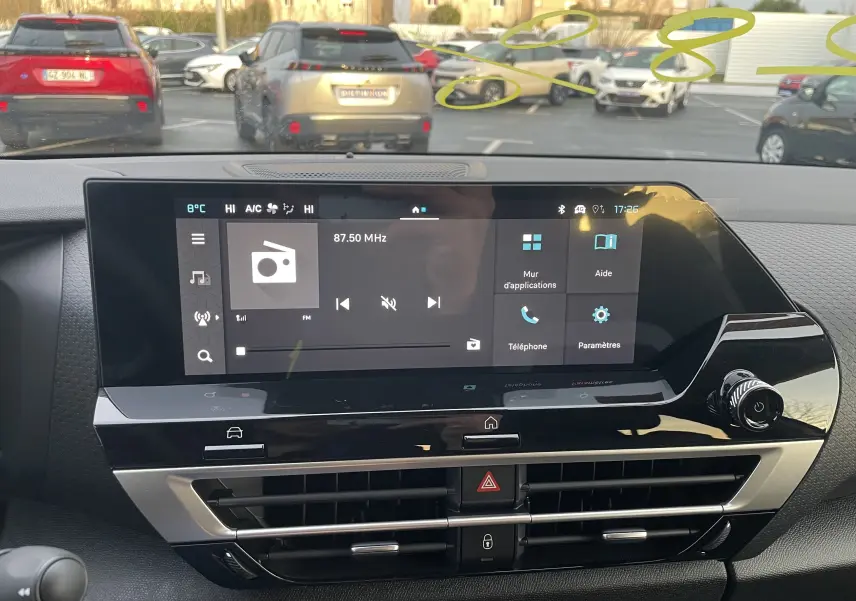 Vue intérieure centrée sur l'écran tactile du tableau de bord de la Citroën C4 hybride blanche avec toit noir.