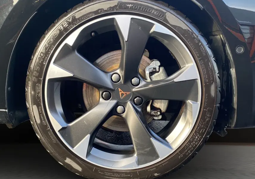 Gros plan sur la jante alliage bi-ton gris et noir d’une CUPRA Leon noire avec logo Cupra au centre.