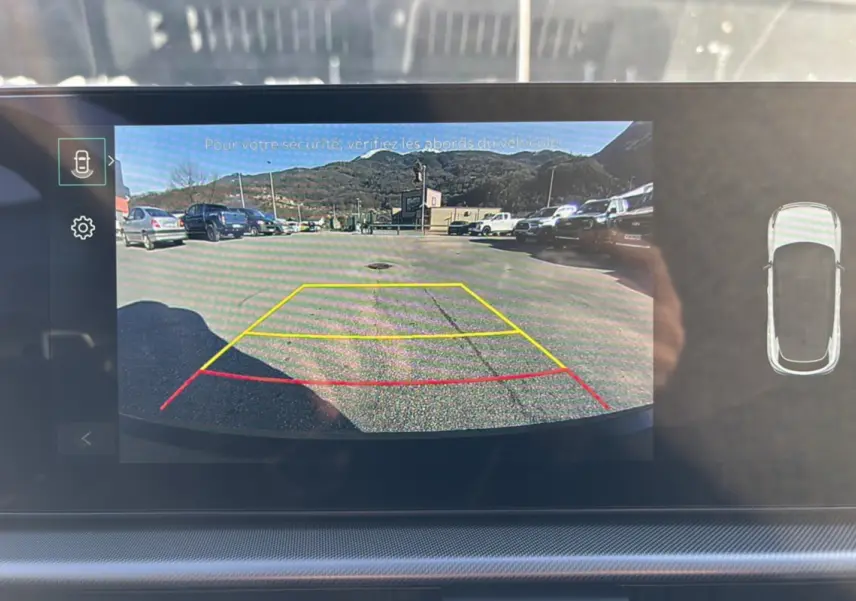 Vue écran caméra de recul du Kia Sportage gris eclipse 2026, avec lignes d’aide au stationnement colorées.