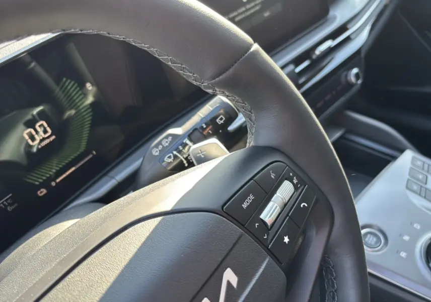 Gros plan sur le volant cuir multifonctions du KIA Sportage gris eclipse, avec tableau de bord numérique en arrière-plan.