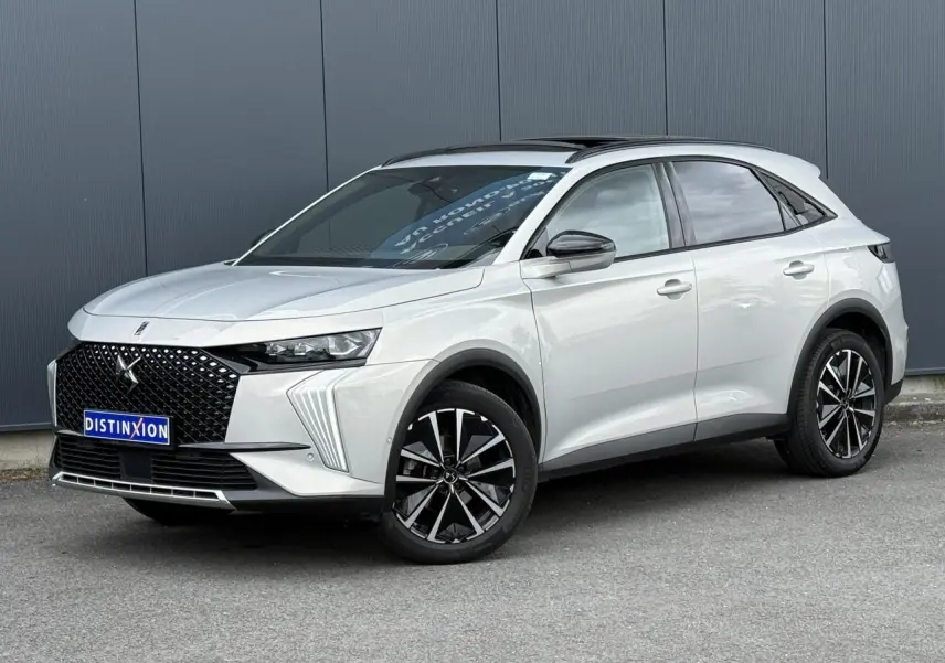 DS7 2025 Cristal Pearl en 3/4 avant droit, avec calandre noire distinctive et jantes alliage 19 pouces.