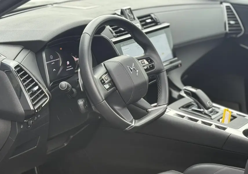 Intérieur noir du DS7 2025 vu côté conducteur, volant cuir avec logo DS et console centrale moderne.
