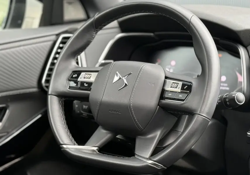 Gros plan sur le volant cuir noir du DS7 2025 avec commandes intégrées et logo DS au centre.