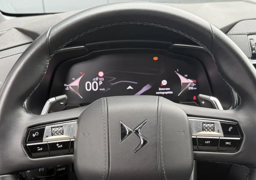 Vue rapprochée du volant en cuir noir avec logo DS et combiné numérique affichant la navigation du DS7 2025.