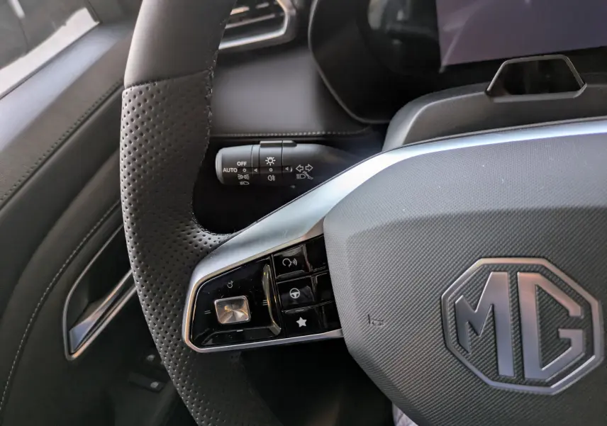 Gros plan sur le volant en cuir noir perforé du MG ZS 2026 avec commandes intégrées et logo MG au centre.