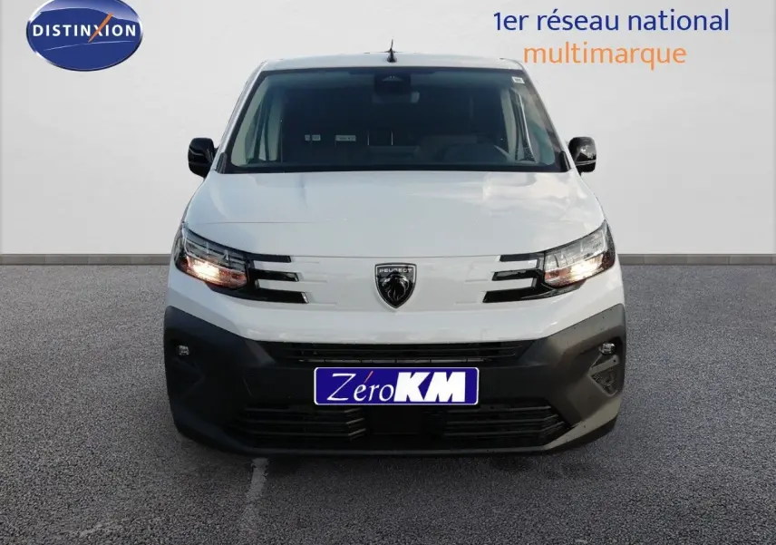 Vue frontale du Peugeot Partner blanc Kaolin 2026 avec calandre noire et phares allumés sur fond neutre.