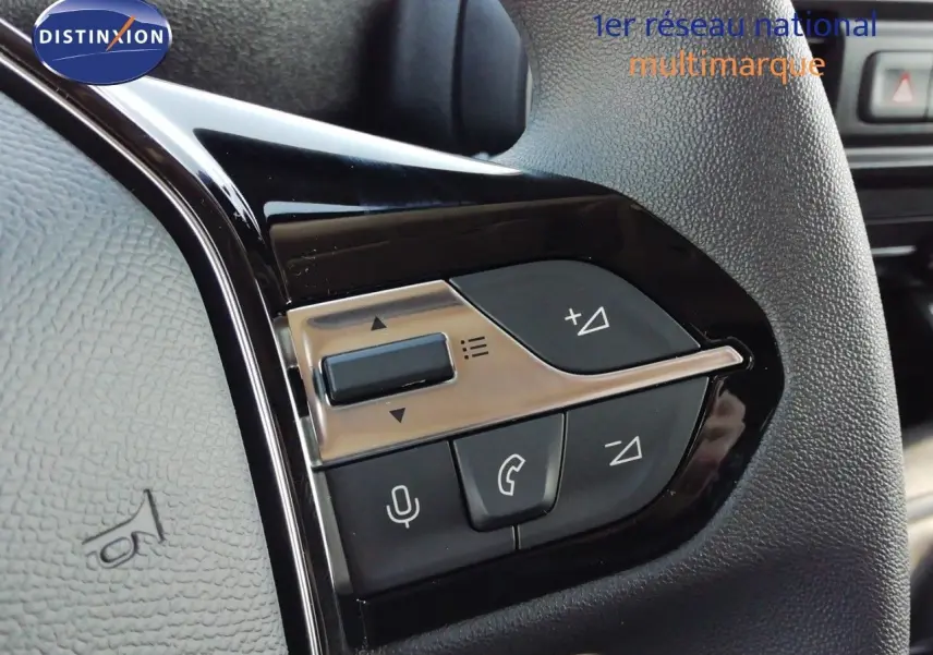 Gros plan sur les commandes multifonctions noires et argentées du volant du Peugeot Partner blanc Kaolin 2026.