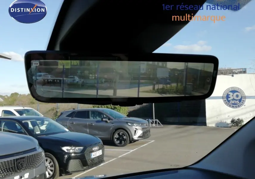 Vue intérieure du rétroviseur numérique montrant un parking avec plusieurs véhicules dont un Peugeot Partner blanc Kaolin à l'arrière.