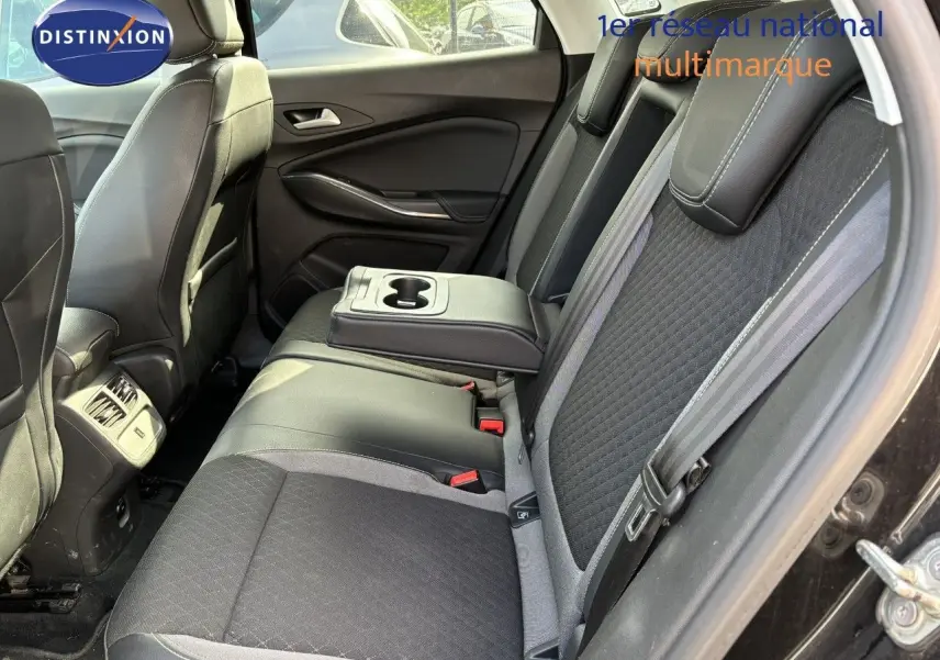 Vue intérieure côté droit des sièges arrière noirs avec accoudoir central et porte ouverte d'un Opel Grandland X 2019.