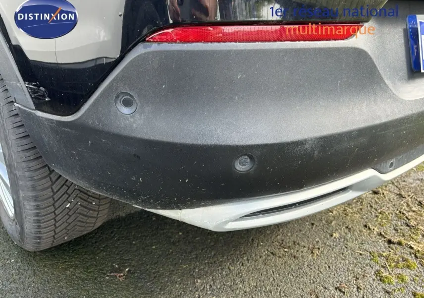 Gros plan sur le pare-chocs arrière noir d'un Opel Grandland X 2019, avec capteurs de recul visibles et feu rouge.