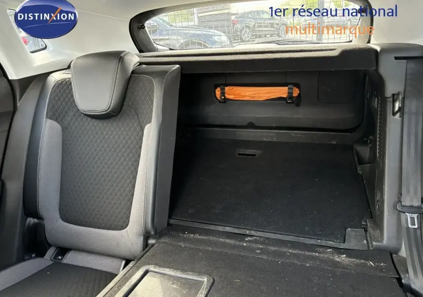 Intérieur du coffre de l'Opel Grandland X noir 2019, siège arrière rabattable et rangement avec trousse de secours orange visible.