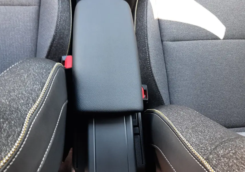 Détail de l'accoudoir central noir entre les sièges avant en tissu gris avec surpiqûres jaunes du Renault Symbioz 2024.