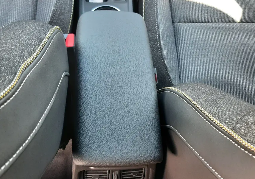 Vue rapprochée de l'accoudoir central noir et des aérateurs arrière entre les sièges tissu gris du Renault Symbioz 2024.