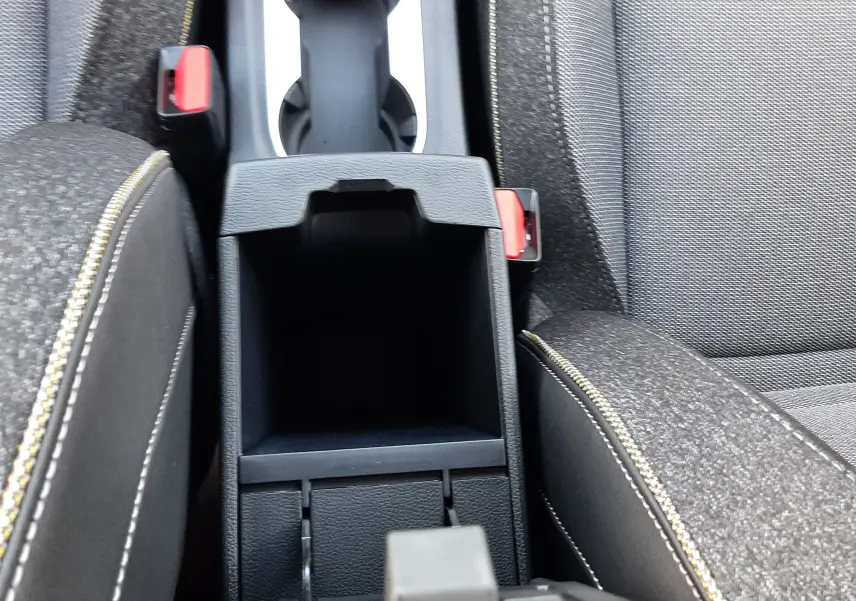 Vue rapprochée de la console centrale ouverte du Renault Symbioz gris Rafale, avec sièges tissu gris et surpiqûres jaunes.