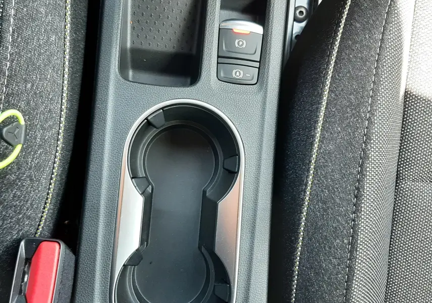 Gros plan sur la console centrale noire du Renault Symbioz 2024, avec porte-gobelets et boutons de frein à main électronique.