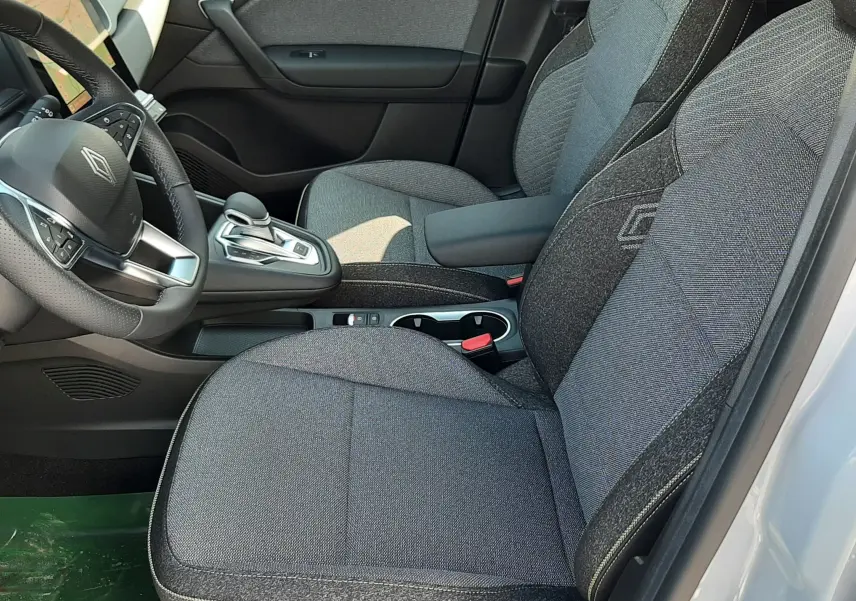 Intérieur avant droit du Renault Symbioz 2024, sièges tissu gris avec logo Renault brodé, console centrale moderne.