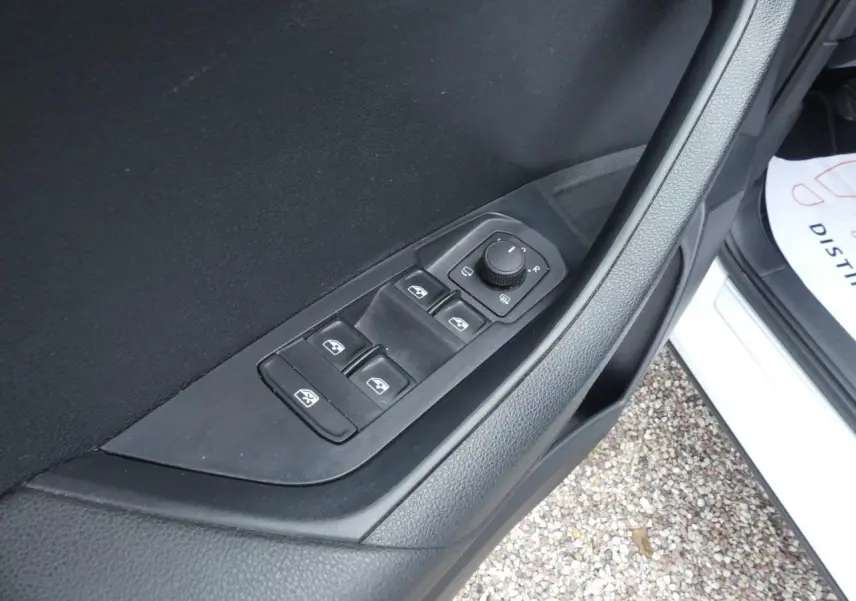 Gros plan sur les commandes de lève-vitres et réglage des rétroviseurs côté conducteur d'un Skoda Karoq blanc 2024.