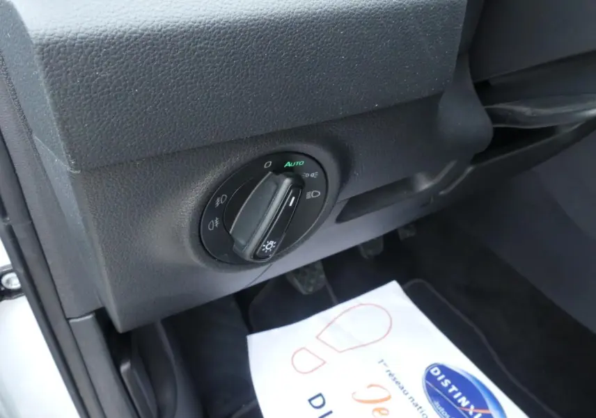 Gros plan sur le bouton de commande des phares côté gauche du tableau de bord du Skoda Karoq blanc 2024.