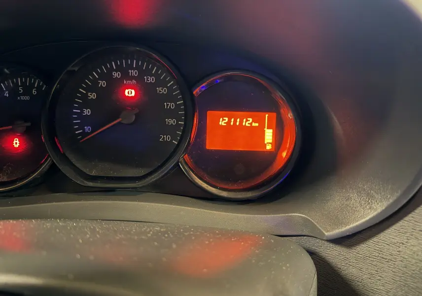 Vue rapprochée du tableau de bord du Dacia Dokker gris, affichant le compteur à 0 km/h et 121112 km au compteur digital.