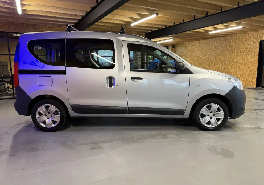 Profil droit d'un Dacia Dokker gris 2019 avec portes coulissantes et jantes en alliage dans un garage éclairé.