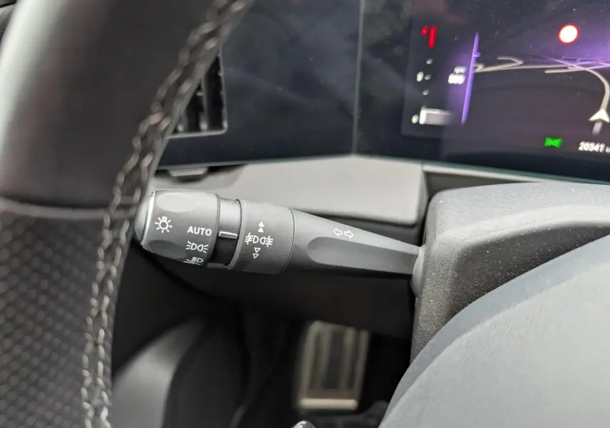 Gros plan sur la commande des feux et clignotants à gauche du volant dans l’Opel Astra gris métallisé 2024.