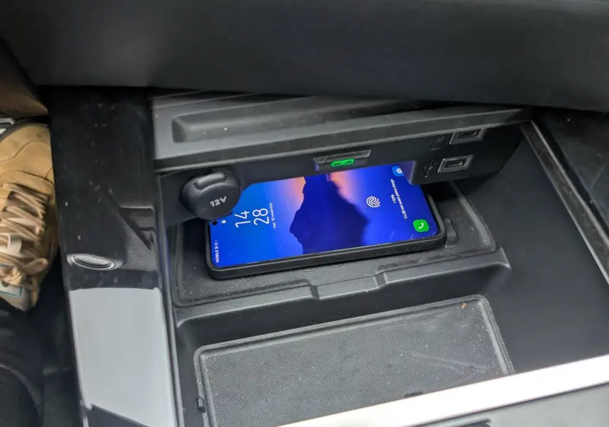 Vue rapprochée de la console centrale de l’Opel Astra 2024 gris métallisé, avec un smartphone posé sur le chargeur sans fil.