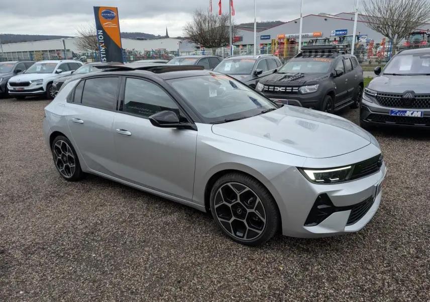 Opel Astra 2024 gris métallisé vue 3/4 avant droit avec toit noir et jantes alliage distinctives.