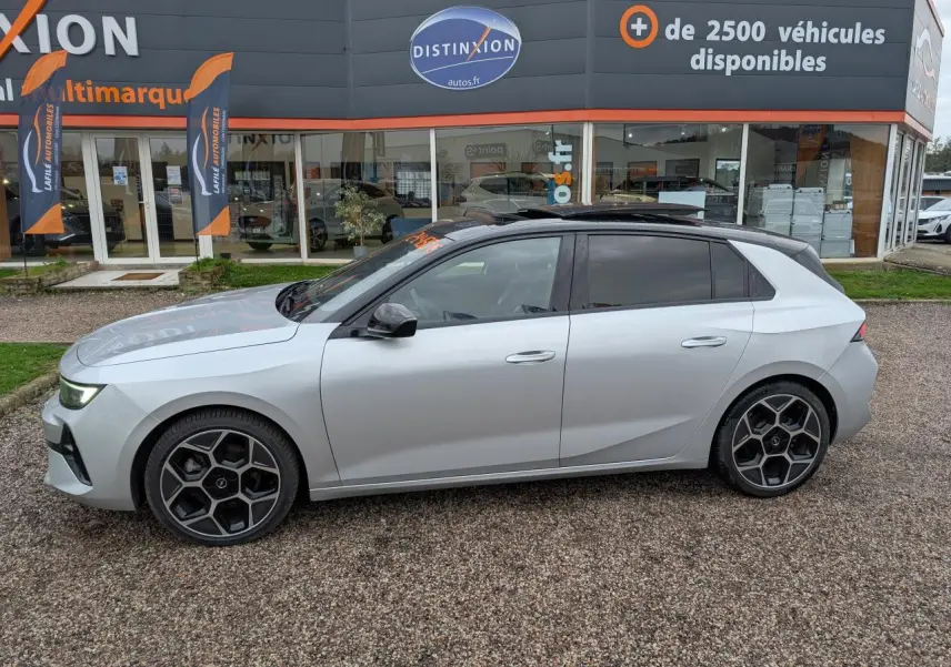 Opel Astra 2024 gris métallisé vue de profil côté gauche, avec toit noir et jantes alliage distinctives.