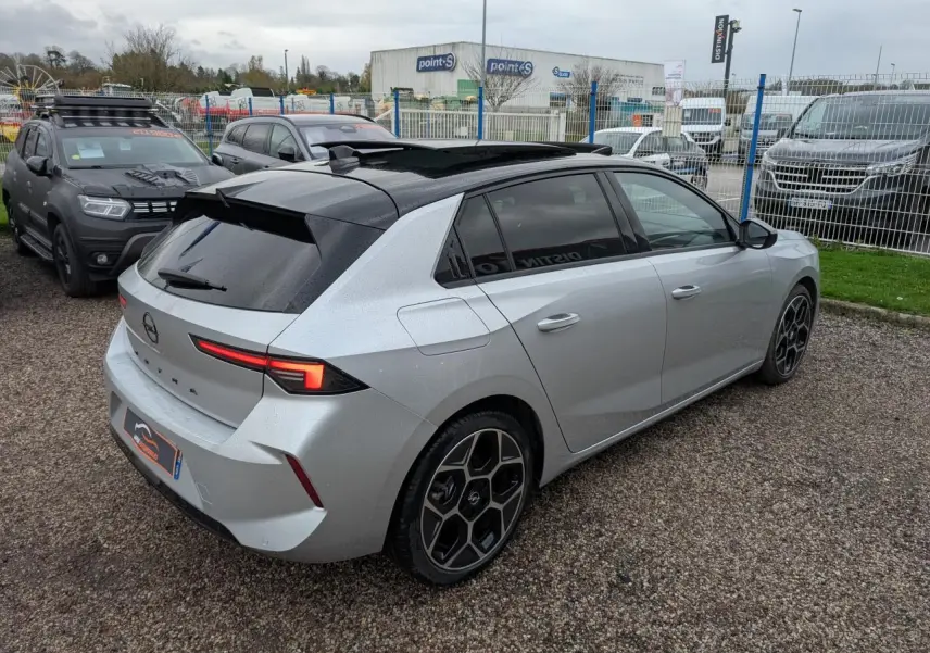 Opel Astra 2024 gris métallisé vue 3/4 arrière droit, toit noir et jantes au design hexagonal distinctif.