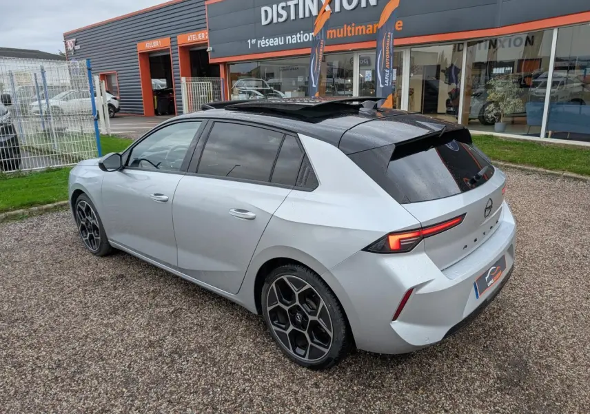 Opel Astra 2024 gris métallisé vue 3/4 arrière droit avec toit noir et jantes distinctives en alliage.