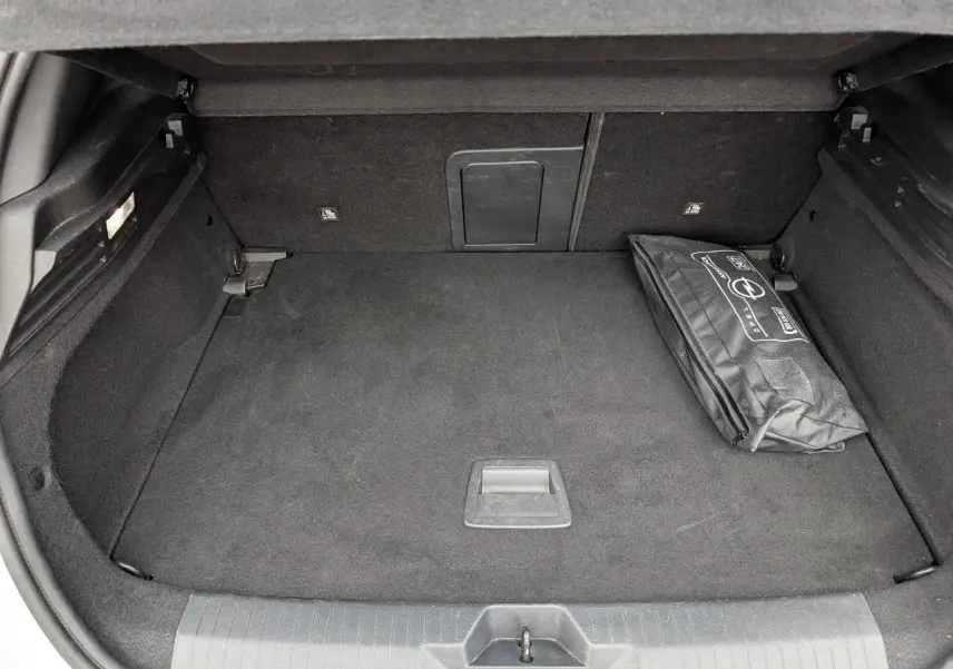 Coffre ouvert d’une Opel Astra 2024 gris métallisé, montrant un espace de rangement avec une trousse de secours noire.
