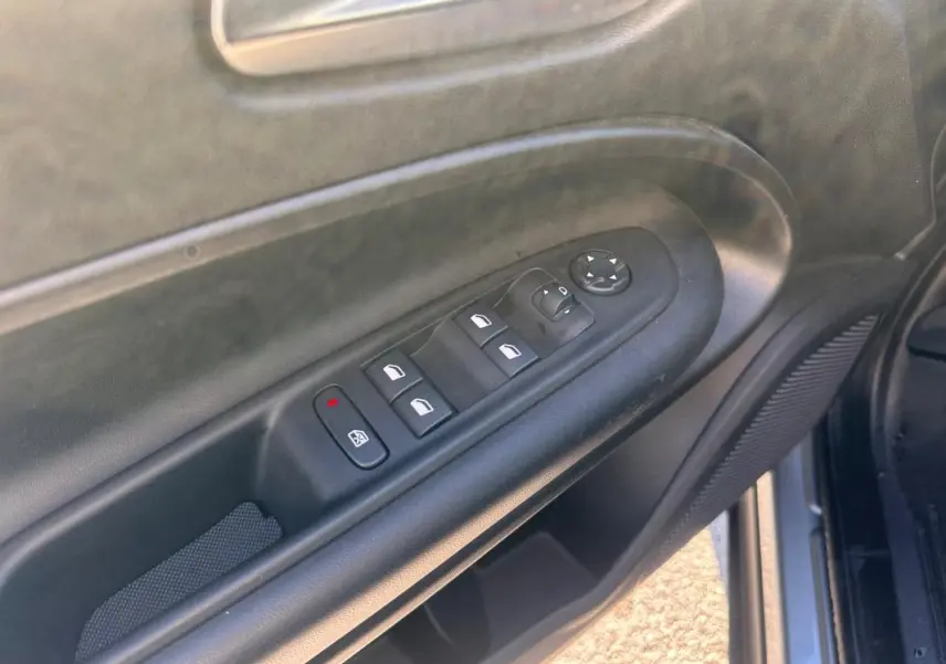 Vue rapprochée du panneau de commandes des vitres électriques côté conducteur du Jeep Avenger gris foncé 2025.