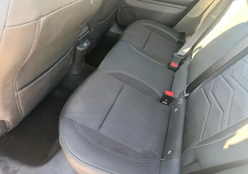 Vue intérieure côté droit des sièges arrière noirs du Jeep Avenger 2025 avec surpiqûres blanches et ceintures de sécurité.