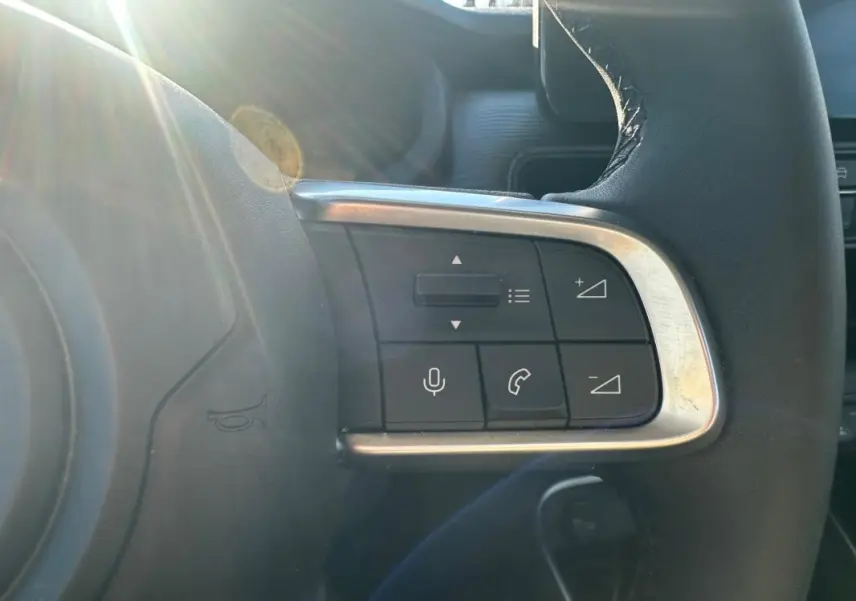 Gros plan sur les commandes à droite du volant cuir du Jeep Avenger gris foncé, avec lumière naturelle.