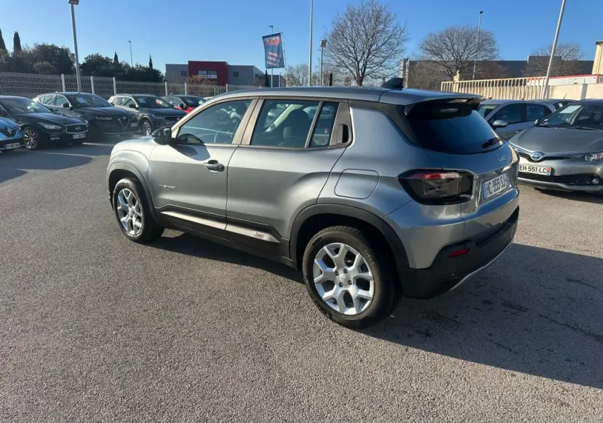 Vue 3/4 arrière droite d'un Jeep Avenger gris foncé avec jantes alliage 17 pouces, dans un parking extérieur.