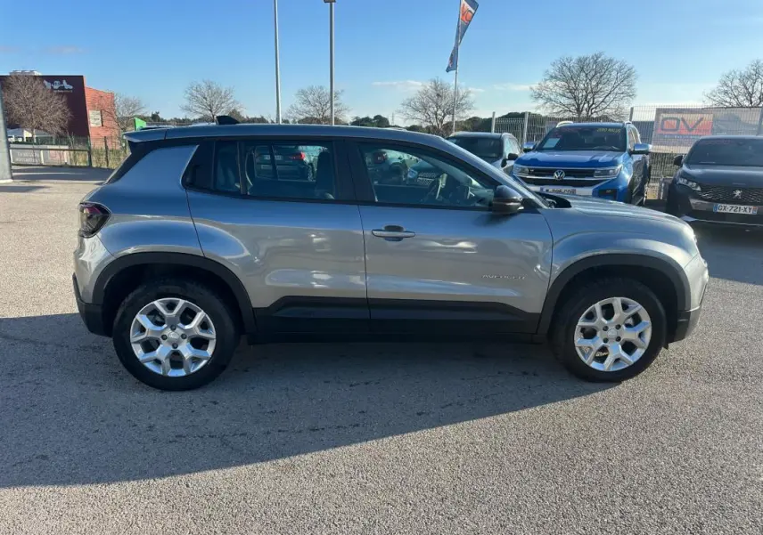 Vue de profil côté gauche d'un Jeep Avenger gris foncé avec jantes alliage 17 pouces sur parking extérieur.