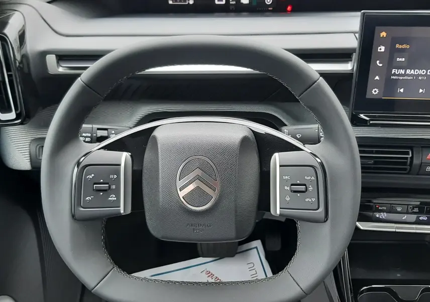 Vue centrée sur le volant de la Citroën C3 Aircross hybride 2025, avec tableau de bord numérique et écran tactile visible.