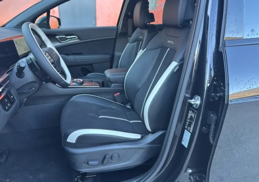 Intérieur côté conducteur du Kia Sportage noir étoilé 2026, sièges sport noirs avec surpiqûres blanches et volant multifonctions.