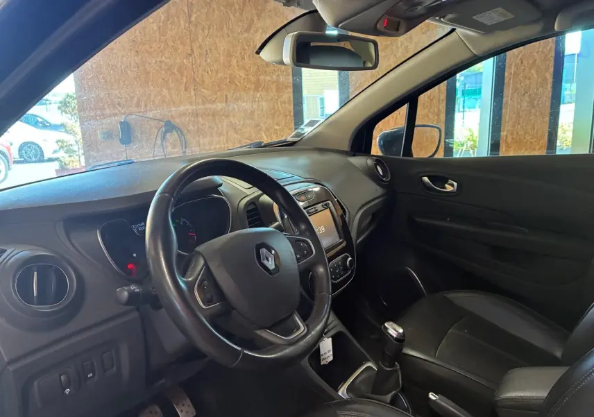 Vue intérieure côté conducteur du Renault Captur bleu 2017, volant multifonction et levier de vitesse manuel visibles.