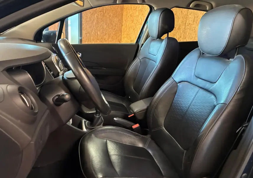 Vue intérieure côté conducteur du Renault Captur bleu 2017, sièges avant en cuir noir avec volant et tableau de bord visibles.