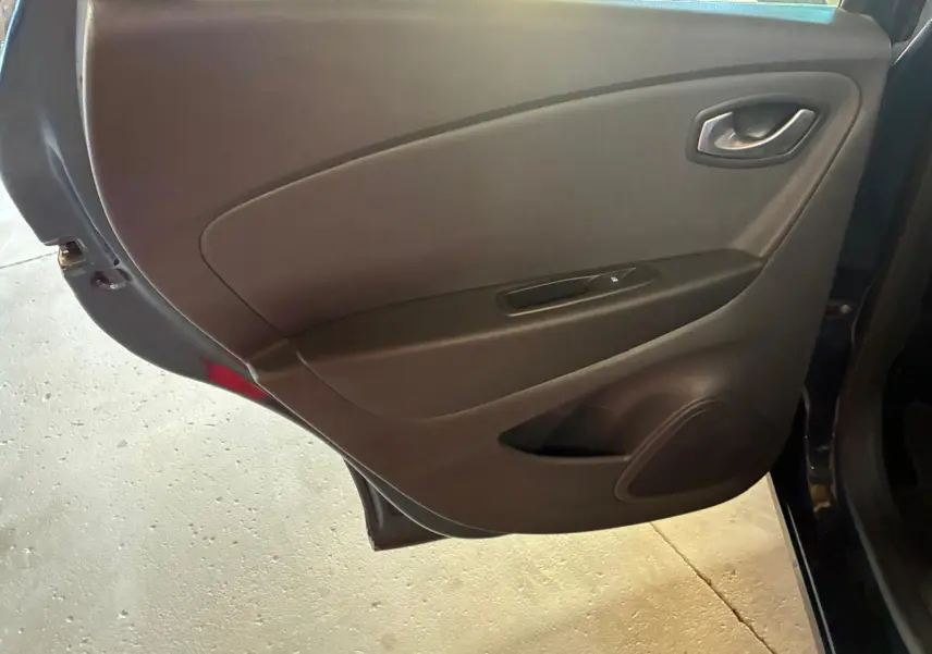 Vue intérieure de la porte arrière droite d’un Renault Captur bleu 2017, panneau noir avec commande de vitre électrique.