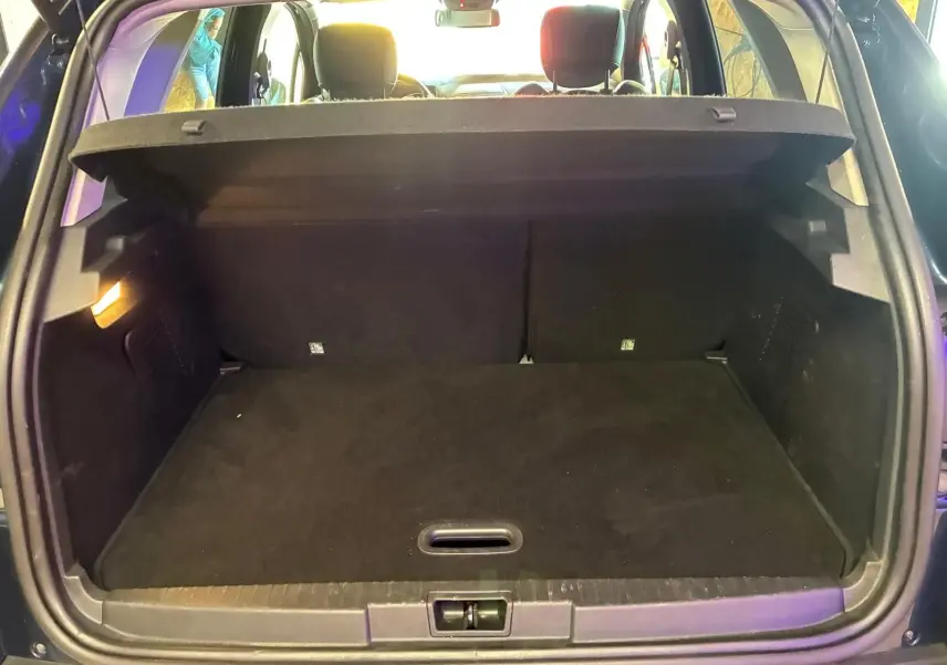 Coffre ouvert vu de l'arrière d'un Renault Captur bleu 2017, montrant un espace de chargement vide et propre.
