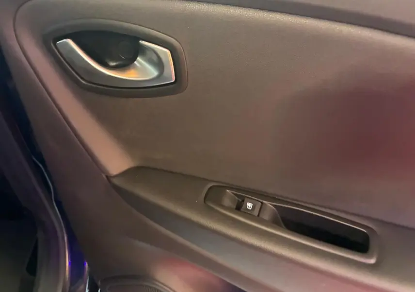 Gros plan sur la poignée intérieure et commande de vitre côté gauche d'une Renault Captur bleu 2017.