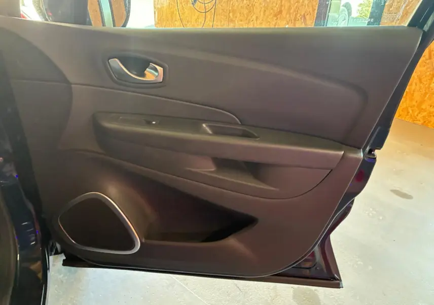 Vue intérieure de la porte avant gauche du Renault Captur bleu, avec poignée argentée et haut-parleur intégré.