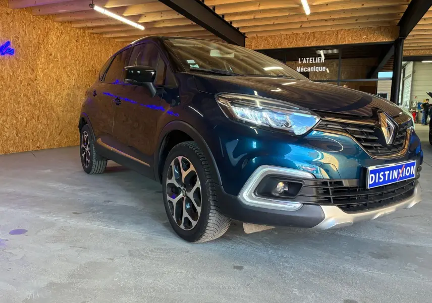 Renault Captur bleu 3/4 avant droit, mettant en valeur ses optiques LED et la calandre distinctive.